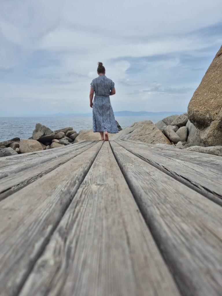 Frau auf einem Steg am Wasser als Symbol für den Weg vom Verstehen ins ehrliche Spüren